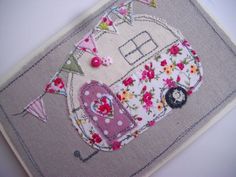 an embroidered piece of fabric with flowers and a camper trailer on it's side