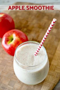 an apple smoothie in a glass next to two apples