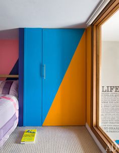 a bedroom with blue, yellow and pink painted on the walls next to a bed