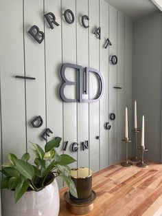 a wooden table topped with a potted plant next to a wall mounted letter sign