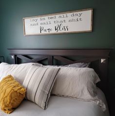 a bed with white sheets and pillows in front of a framed sign on the wall