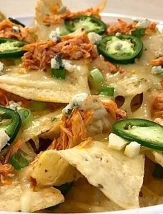 a bowl filled with nachos covered in cheese and toppings, including jalapenos