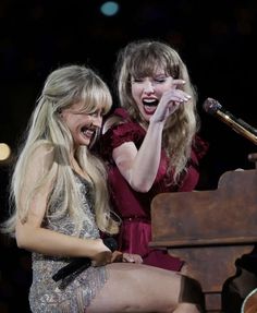 two women laugh as they perform on stage