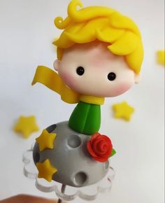 there is a small plastic doll on top of a ball with stars around it and a rose in the middle