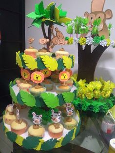 there is a jungle themed cake and cupcakes on the table