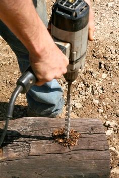 a man using a drill to cut wood with a power tool on top of it