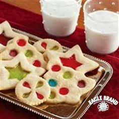 some cookies are on a metal tray with glass of milk