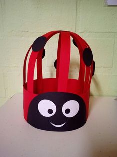 a red paper crown with black dots and a ladybug design on the front