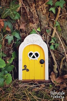 a small yellow door with two eyes on it in front of a tree and ivy