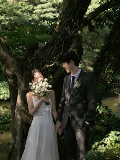 a bride and groom standing next to each other in front of a tree with white flowers