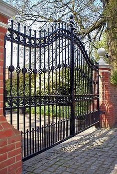 a brick wall and gate in front of a tree