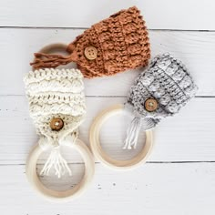 three crocheted items are sitting on a white wooden surface and one is holding a ring