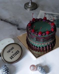 the cake is decorated with cherries and has a name tag on it next to some candies