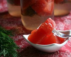 a spoon full of watermelon slices on a red tablecloth with pine needles