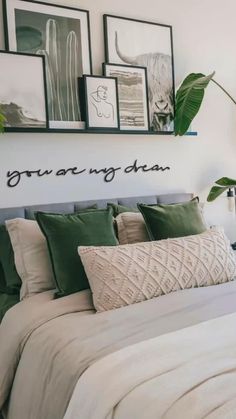 a bed with green pillows and pictures on the wall