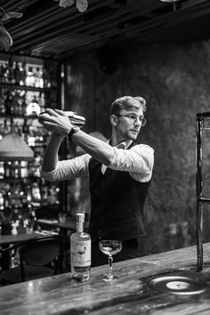 a man standing in front of a wooden table with a wine glass on top of it