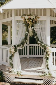 a white gazebo decorated with flowers and greenery