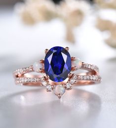 a ring with an oval blue sapphire surrounded by white opal and diamonds on a table