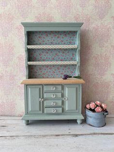 a dollhouse furniture set with flowers on the wall and a flower pot next to it