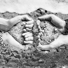 black and white photograph of two hands holding sand