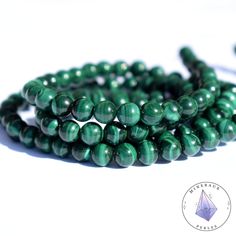 the beads are green and have been set on a white surface with a diamond in the middle