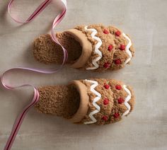 two gingerbread cookies with white frosting and red cherries on them are next to a pink ribbon