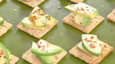 crackers with various toppings are arranged on a green tray, ready to be eaten