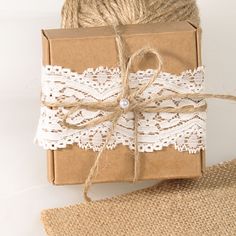 a brown box wrapped in twine and tied up with white lace next to burlap