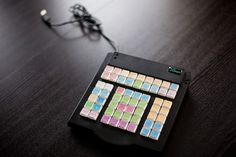 an electronic device with many different colored squares on the top and bottom, sitting on a wooden table