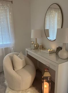 a white chair sitting in front of a mirror next to a table with a lamp