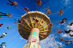 an amusement park ride with people riding on the rides and flying in the blue sky