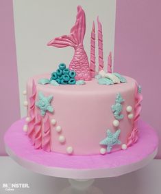 a pink and blue cake decorated with stars, mermaid tail, sea shells and seashells