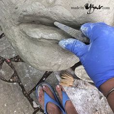 a person with blue gloves is painting a rock