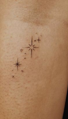 a small star tattoo on the back of a woman's thigh, with stars in it