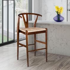 a wooden chair sitting in front of a counter with flowers on the table next to it