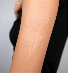 a woman with a tattoo on her arm that has a flower drawn on the side