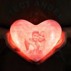 a person holding a heart shaped light up with the image of a man and woman on it