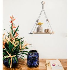 a wooden table topped with two vases filled with flowers next to a wall shelf