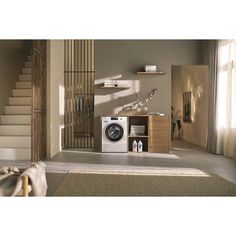 a washer sitting in the middle of a living room next to a stair case