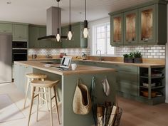 a kitchen with green cabinets and stools next to an island in front of the sink