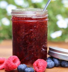 raspberry jam in a jar with blueberries and raspberries next to it