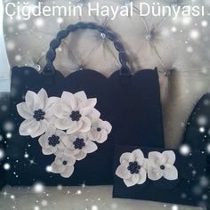 two black bags with white flowers on them sitting on a couch next to a pillow