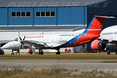 two airplanes are parked on the tarmac at an air port run way with hangars in the background