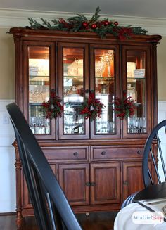 a wooden china cabinet with christmas decorations on top