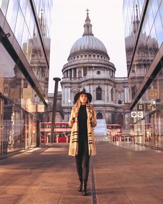 a woman is walking down the sidewalk in front of some glass buildings and a domed building