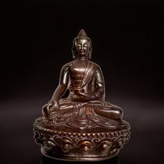 a bronze buddha statue sitting on top of a table