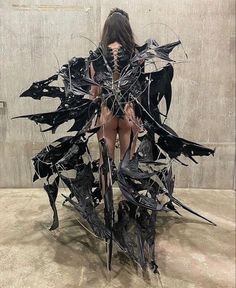 a woman sitting on top of a pile of black pieces of paper in front of a wall