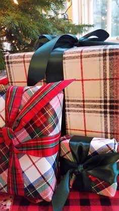 three wrapped presents sitting on top of a red and black checkered blanket next to a christmas tree