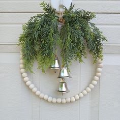 two bells hanging from the side of a garage door decorated with evergreen and white beads