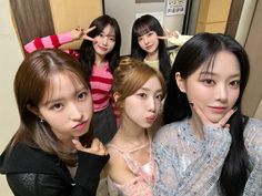 four young women posing for a photo in front of a mirror with their hands on their chins